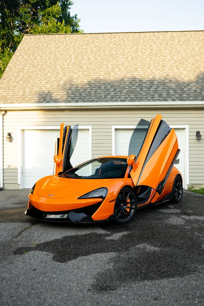 Orange McLaren with doors raised after paint and finish work