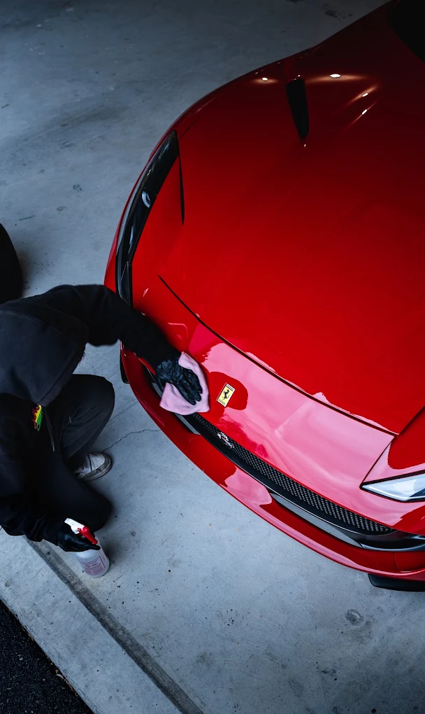 Detailer wiping down the hood of a red Ferrari 812