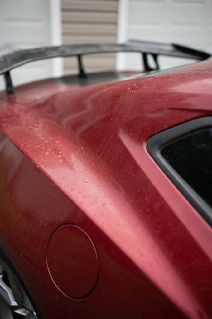 Dull red paint with water spots and grime before ceramic coating